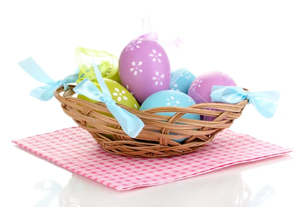 Colorful easter eggs in basket on napkin isolated on white — Stock Photo, Image