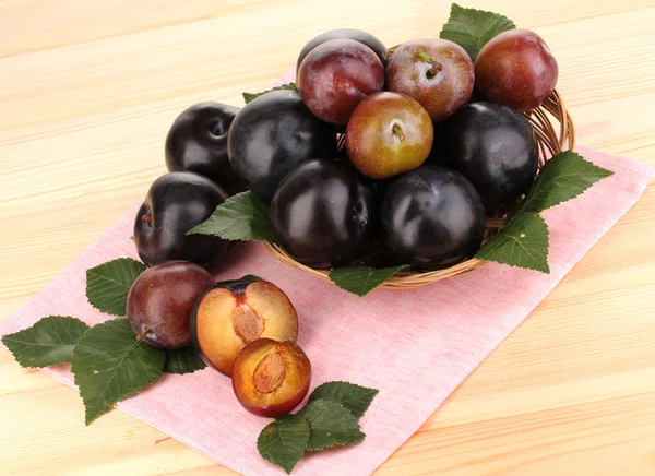 Rip plums on basket on wooden table — Stock Photo, Image