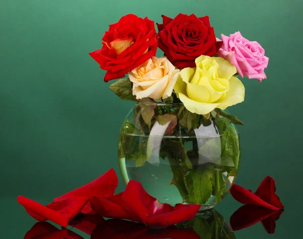 Beautiful roses in glass vase on green background — Stock Photo, Image