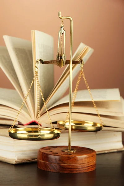 Gouden schalen van Justitie en boeken over bruine achtergrond — Stockfoto