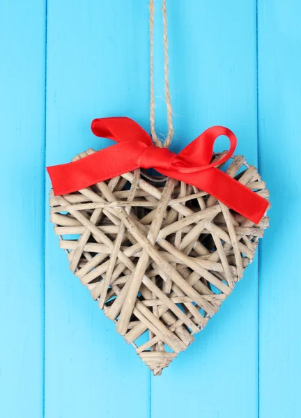 Wicker heart with red bow on wooden background — Stock Photo, Image