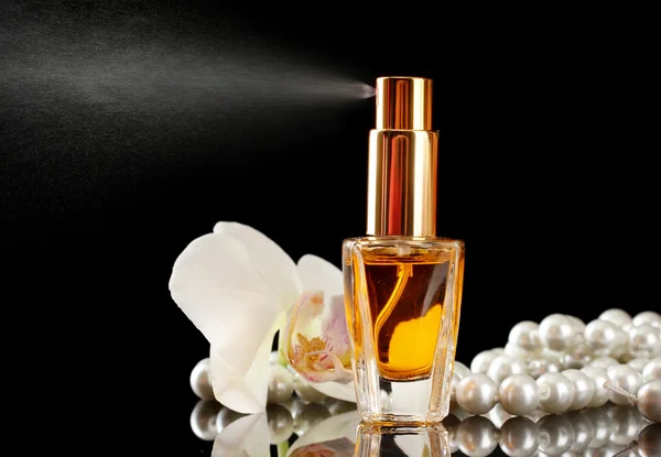 Perfume de mujer en hermosa botella y flores de orquídea, sobre fondo negro — Foto de Stock