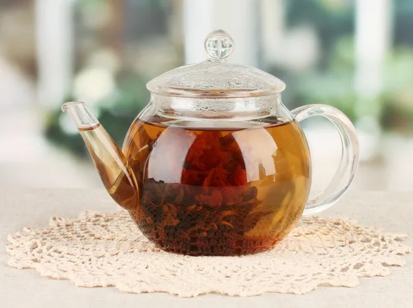 Exotic green tea with flowers in glass teapot on bright background — Stock Photo, Image