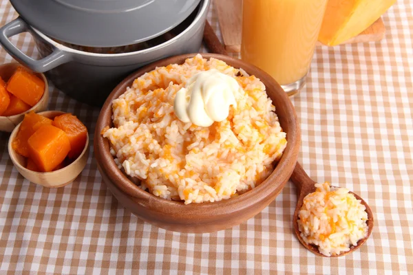 Taste rice porridge with pumpkin and glass of juice on tablecloth background — Stock Photo, Image