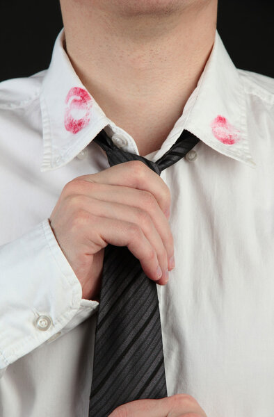 Lipstick kiss on shirt collar of man, isolated on black
