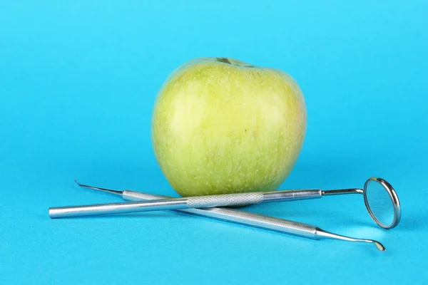Зеленое яблоко и стоматологические инструменты на цветном фоне — стоковое фото