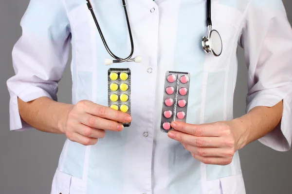 Primo piano della mano medico femminile che tiene pillole, su sfondo a colori — Foto Stock