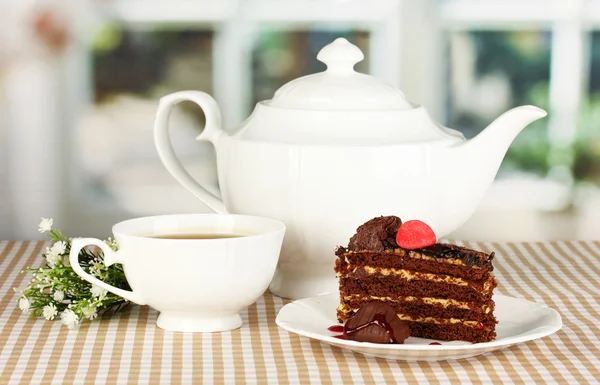 Tetera, taza de té y delicioso pastel en el fondo de la ventana — Foto de Stock