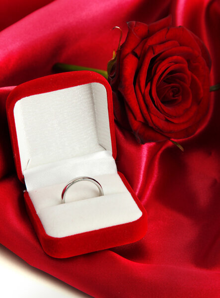 Beautiful box with wedding ring and rose on red silk background