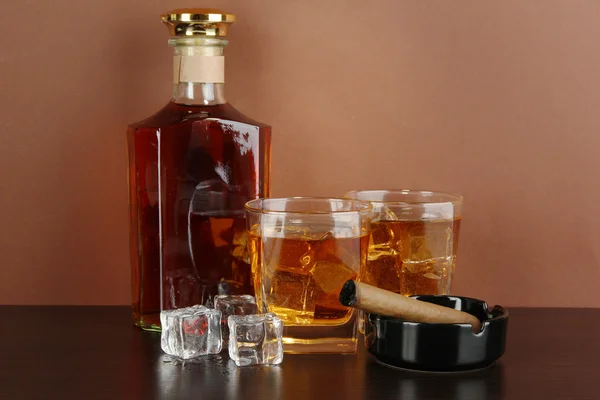 Botella y vasos de whisky y cigarro sobre fondo marrón —  Fotos de Stock