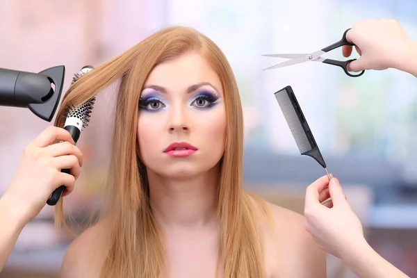 Beautiful woman and hands with brushes, scissors and hairdryer in beauty salon — Stock Photo, Image