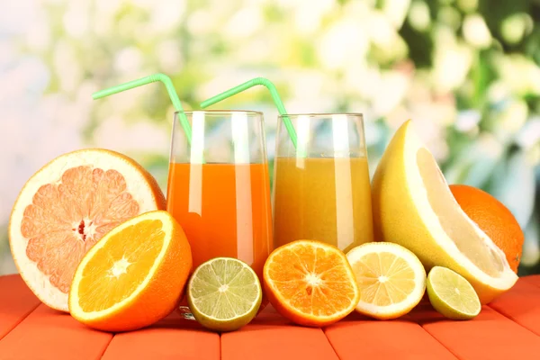 Lots ripe citrus with juices on wooden table on natural background — Stock Photo, Image