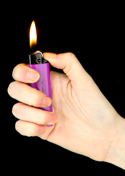 Burning lighter in female hand, isolated on black