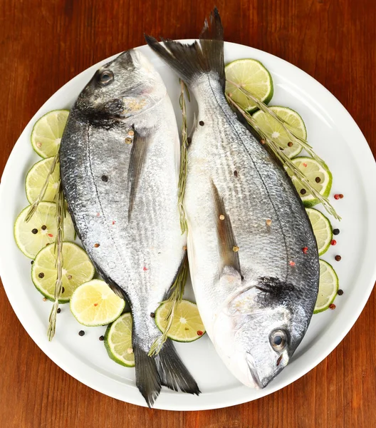 Due dorado di pesce con limone su piatto su tavolo di legno primo piano — Foto Stock