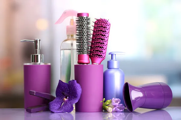 Hair brushes, hairdryer, straighteners and cosmetic bottles in beauty salon — Stock Photo, Image