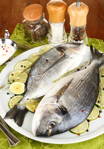 Two fish dorado with lemon on plate on wooden table close-up — Stock Photo, Image