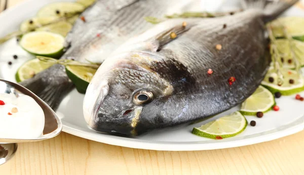 Dua ikan dorado dengan lemon di piring di atas meja kayu close-up — Stok Foto