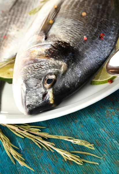 Dua ikan dorado dengan lemon di piring di meja kayu biru close-up — Stok Foto