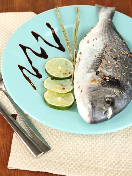 Fish dorado with lemon on plate on wooden table close-up — Stock Photo, Image