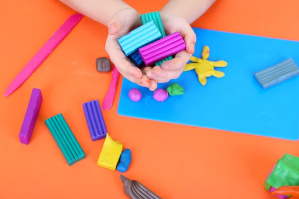 Manos de niño sosteniendo plastilina sobre el escritorio —  Fotos de Stock