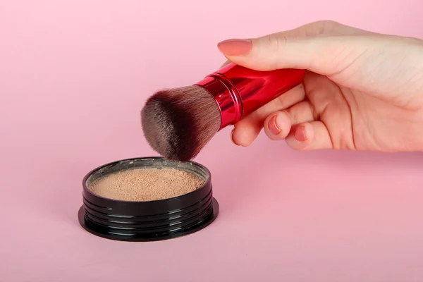 Powder and brush in hand on pink background — Stock Photo, Image
