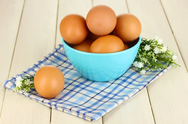 Eier in blauer Schüssel auf Holztisch in Großaufnahme — Stockfoto