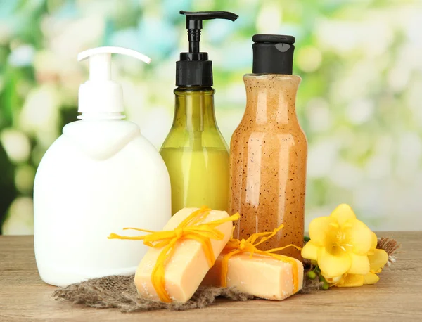 Liquid and hand-made soaps on wooden table, on green background — Stock Photo, Image