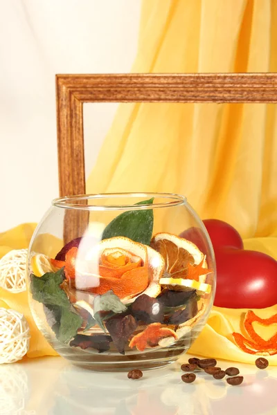黄色の布の背景にガラスの花瓶のオレンジの皮を乾燥から装飾的なバラ — ストック写真