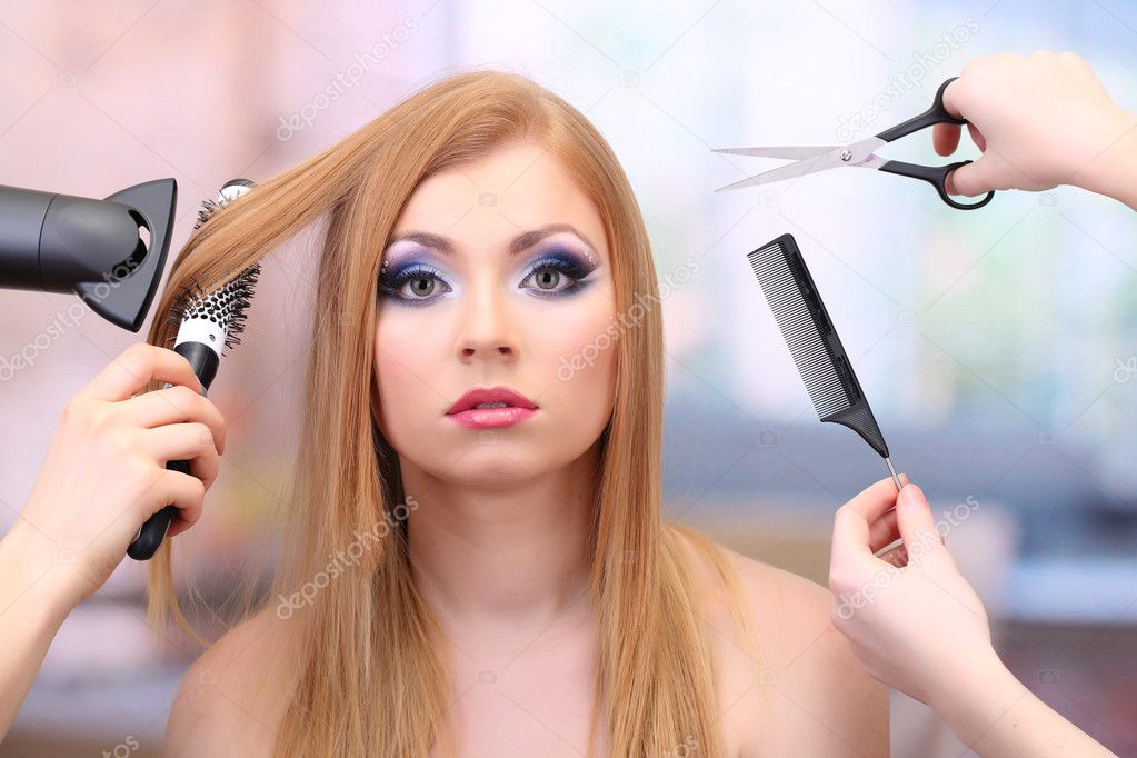 Beautiful woman and hands with brushes, scissors and hairdryer in beauty salon