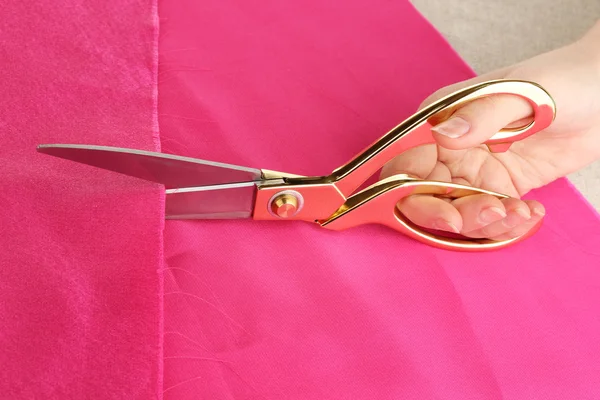 Costurera corte tela rosa sobre fondo de tela beige —  Fotos de Stock