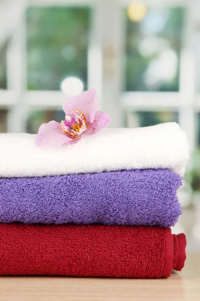 Pilha de toalhas com flor perfumada no fundo da janela — Fotografia de Stock