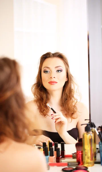 Joven hermosa mujer haciendo maquillaje cerca del espejo — Foto de Stock