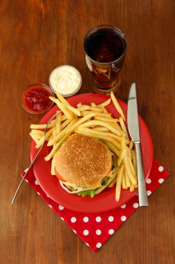 patates kızartması ve ahşap zemin üzerinde soğuk içecek ile lezzetli peynirli burger