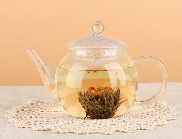 Egzotikus zöld tea virágok üveg teáskanna asztalon, a háttér színét. Folyamat, hogy a tea — Stock Fotó