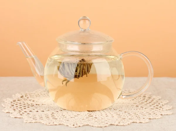 Exotic green tea with flowers in glass teapot on table on color background.Process of making tea — Stock Photo, Image