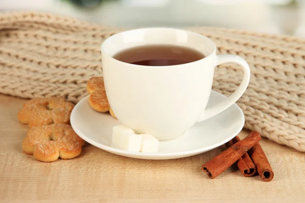 Cup of tea with scarf on table in room — Stock Photo, Image