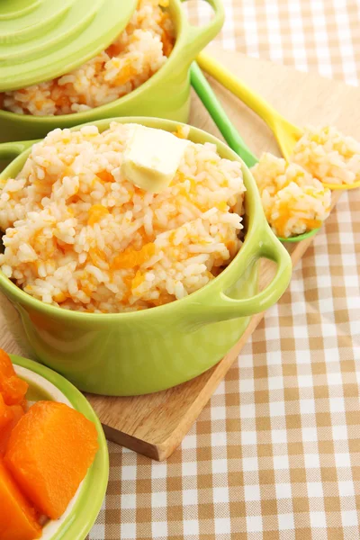 Taste rice porridge with pumpkin in saucepans on tablecloth background — Stock Photo, Image