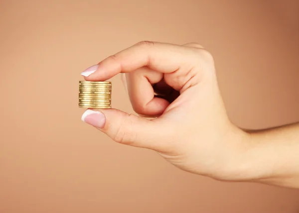 Mãos de mulher com moedas no fundo marrom — Fotografia de Stock