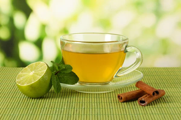 Tasse Tee mit Minze, Limette und Zimt auf Tisch vor hellem Hintergrund — Stockfoto