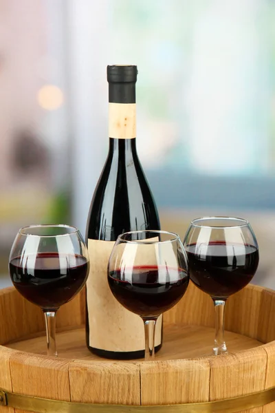 Botella de vino y copas en bandeja de madera, sobre fondo brillante —  Fotos de Stock