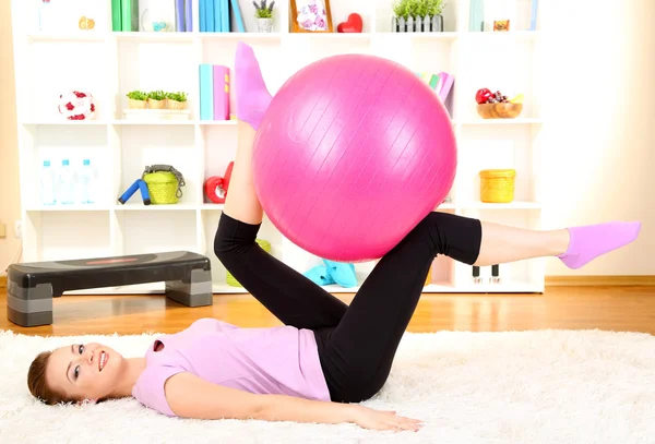 Mujer joven haciendo ejercicios de fitness con pelota de gimnasio en casa — Foto de Stock