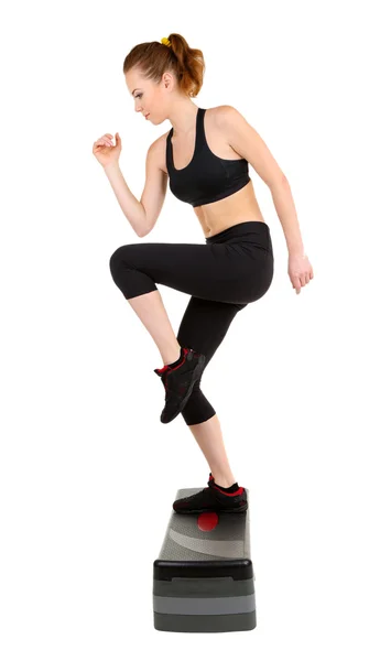 Ung kvinna göra fitnessövningar på stepper isolerad på vit — Stockfoto