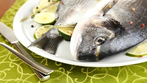 Two fish dorado with lemon on plate on wooden table close-up — Stock Photo, Image