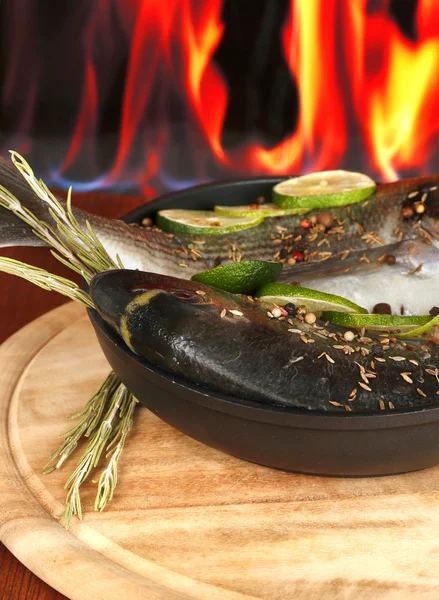 Two fish dorado with lemon on pan on wooden table on fire background — Stock Photo, Image