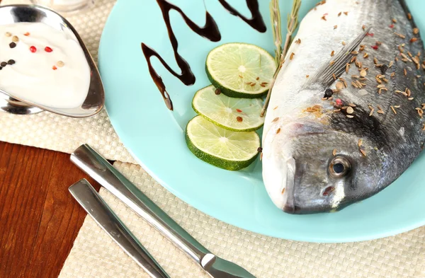 Fish dorado with lemon on plate on wooden table close-up — Stock Photo, Image