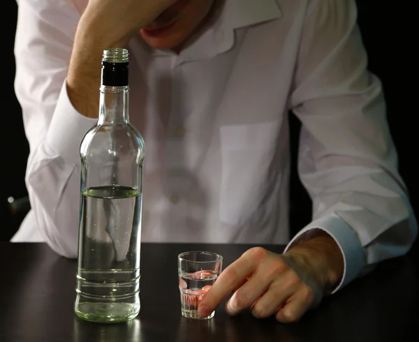 Hombre con botella de alcohol, sobre fondo negro —  Fotos de Stock