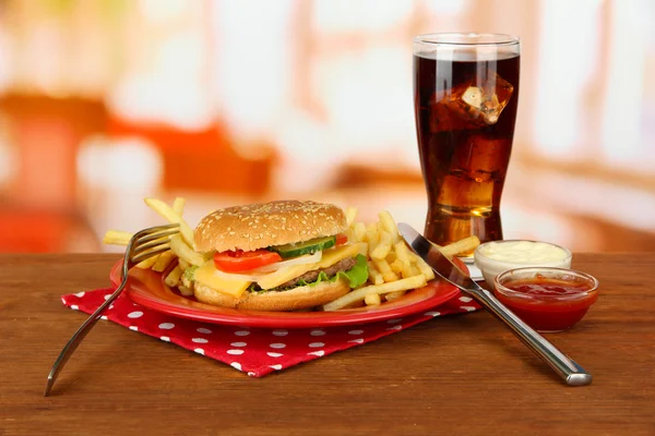 Hambúrguer de queijo saboroso com batatas fritas e bebida fria, em fundo brilhante — Fotografia de Stock