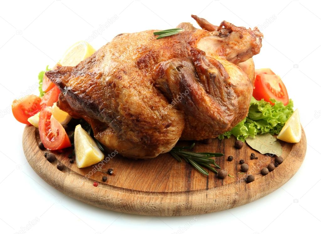 Whole roasted chicken on wooden plate with vegetables, isolated on white