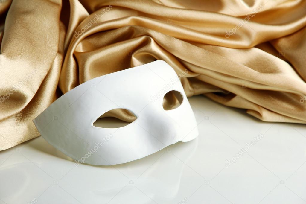 White mask and golden silk fabric, isolated on white