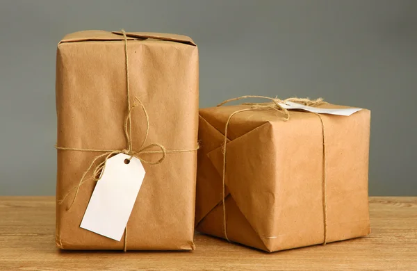 Cajas de paquetes con papel kraft, sobre mesa de madera sobre fondo gris —  Fotos de Stock